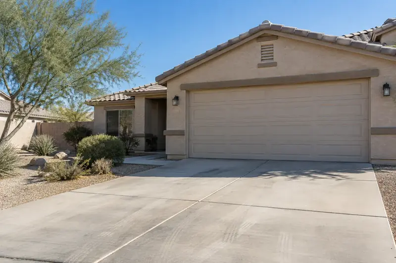Two-car garage door on a stucco Phoenix home with desert landscaping in late-morning light